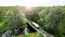 Aerial. The Fuel Gasoline Truck Is Crossing The Little Rural Bridge. Beautiful Nature Around. View Above From Drone.