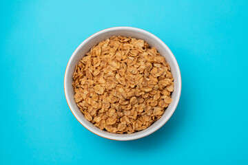 Sticker - flakes wheat in the bowl on blue background