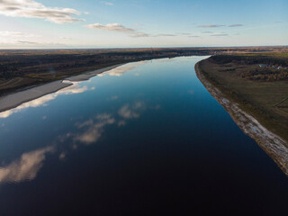 Two banks of a large river. Reflection of the sky in the water