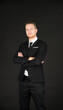 © Arunporn - Portrait of young smart confident and successful businessman in black suit with arm crossed on isolated black background