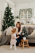 Little Girl With Mom Decorating Christmas Tree At Home