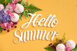 © Maki Company Limited/Stocksy - Hello summer text on yellow background with colorful background. Top view, flat lay.