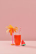 © Maki Company Limited/Stocksy - Summer watermelon drink in glass with sliced fruit and tree made of paper on orange background with space for text