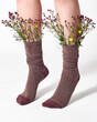 © Yaroslav Danylchenko/Stocksy - Woman wearing brown socks with wild flowers sticking out.