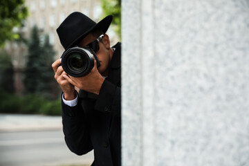 Private detective with modern camera spying on city street