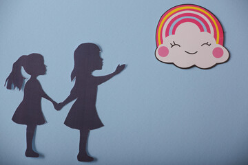 silhouette of little girls in the clouds and a rainbow on a blue background