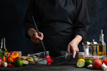 The professional chef brushed glass bowl for baking potato. Backstage of cooking traditional asian dish with seafood. Preparing delicious meal on dark blue background. Concept of cooking process.