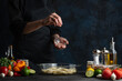 © Anton - The professional chef squeezes lime juice on raw potatoes. Backstage of cooking traditional asian dish with seafood. Preparing delicious meal on dark blue background. Concept of cooking process.