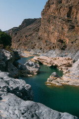 Wall Mural - a river with a rocky cliff and a blue sky