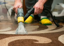 The Process Of Cleaning Carpets With A Steam Vacuum Cleaner. An Employee Of A Cleaning Company Cleans The Carpet Using Steam.