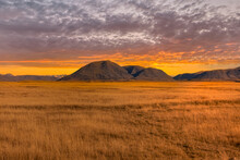 The Mountains And Dry Tussock Covered Valley Floor At Hakatere Conservation Park In The Ashburton Highlands Under A Vibrant Sunset Sky