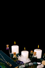 Magic potions, ancient book, crystals with stones and candles isolated on a black background. Copy space.