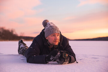 Male landscape photographer takes pictures of colorful winter sunset. Winter wonderland with purple colors.