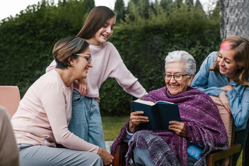 Wall Mural - latina women family reading a book in a backyard outside home in Mexico city