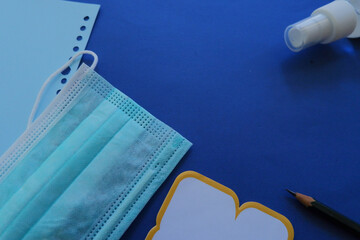 Sticker - Shot of a medical mask, sanitizer, and a blank card on a blue background