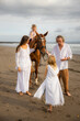© Olga - Horse riding. Little pretty girl on a horse. Father leading horse by its rein and talking to daughter. Wife stroking a horse. Family concept. Summer holidays. Bali, Indonesia