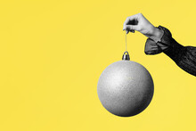 Gray Christmas Ball In Female Hand On Grey Background
