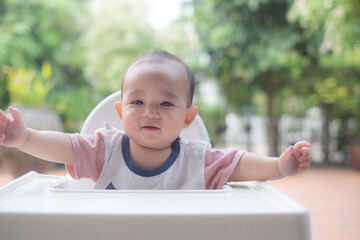 Baby is sitting on the baby's chair preparing for the meal in the garden