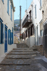 Naklejka na meble A narrow, winding street in a Mediterranean town with white walls, blue windows and stone steps.