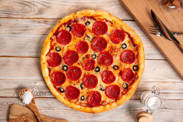 Wall Mural - Top view on fresh baked pepperoni pizza with salami and olives on the wooden table