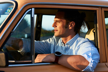 Sticker - Closeup shot of a man sitting on the front seat of his vintage brownish car. Vehicle in motion