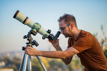 Wall Mural - amateur astronomer looking at the sky with a telescope.