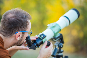 Wall Mural - amateur astronomer looking at the sky with a telescope.