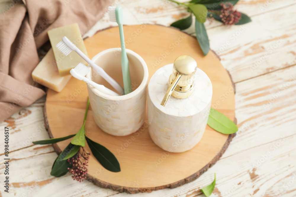 Board with dispenser and toothbrushes on wooden table