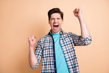 Sticker - Portrait of attractive cheerful crazy guy wearing checked shirt rejoicing isolated over beige pastel color background