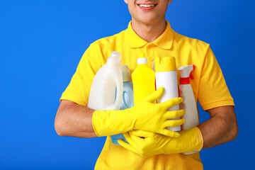 Poster - Young man with cleaning supplies on color background