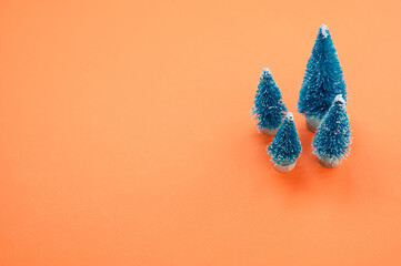 Wall Mural - Closeup of Christmas pine figurines on orange surface for a copy space