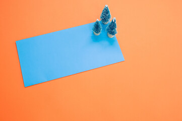 Wall Mural - Closeup of Christmas pine figurines on orange and blue background for a copy space