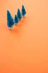 Wall Mural - Vertical shot of Christmas pine figurines on orange surface for a copy space