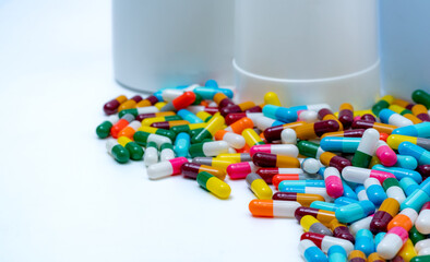 Wall Mural - Selective focus on colorful antibiotic capsule pills on blur plastic drug bottle. Antibiotic drug resistance concept. Pharmaceutical industry. Healthcare and medicine. Pharmaceutical manufacturing.