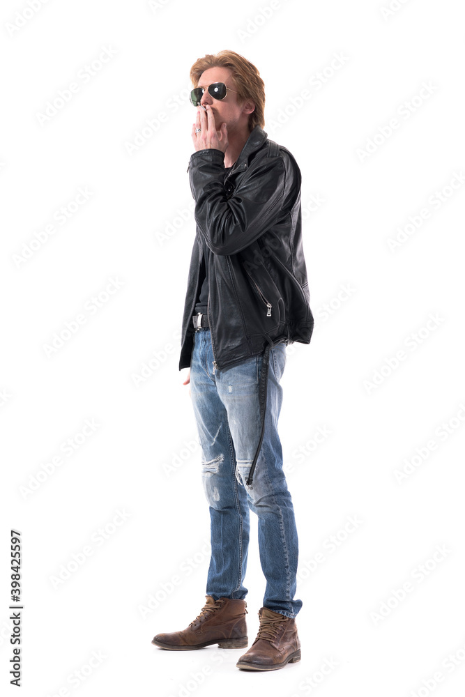 Side view of confident man in biker or rocker style clothes smoking cigarette looking away. Full body length isolated on white background. Stock-bilde