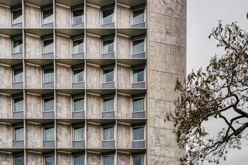 Modern German architecture on a residential building conveys a concept of shared living space or sharing accommodation. Square windows pattern and closed curtains on a contemporary facade bear privacy