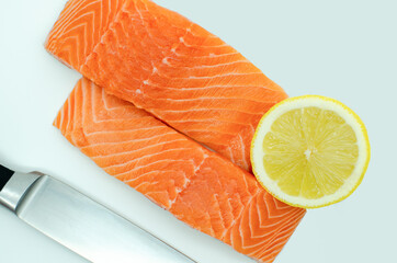 Two slices of fresh salmon filet, top view white background. knife and lemon