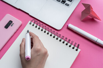 Canvas Print - High angle shot of a laptop, a cellphone, and writing tools on a pink surface