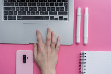 Canvas Print - High angle shot of a laptop, a cellphone, and writing tools on a pink surface