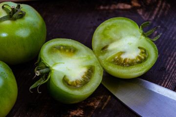 Canvas Print - High angle shot of sliced green tomatoes with knife on a wooden table