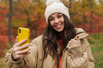 Wall Mural - Brunette happy woman in knit hat taking selfie