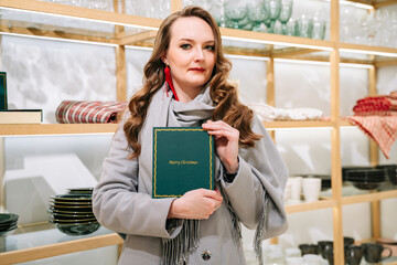 Beautiful woman holding a Christmas gift book in the store.