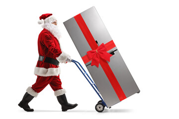 Poster - Full length portrait of a santa claus pushing a fridge with a red bow on a hand truck