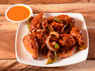 Chicken chilly momo with sauce served over a rustic wooden background, selective focus