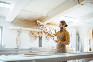 Wall Mural - Handsome carpenter checking the quality of the window frame before the paint at the carpentry workshop