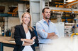 © Daniel Ingold/Westend61 - Smiling businesswoman and male entrepreneur with arms crossed standing in industry