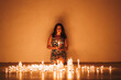 © Javier De La Torre Sebastian/Westend61 - Woman with lit candles against wall in darkroom at home