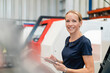 © Daniel Ingold/Westend61 - Smiling businesswoman holding digital tablet standing against machinery in factory