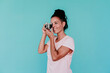 © Eva Blanco/Westend61 - Smiling woman photographing with old-fashioned camera against turquoise background