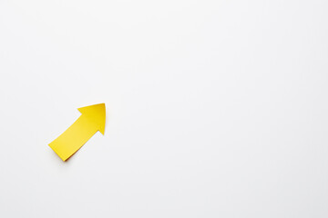 Wall Mural - Right-up yellow paper arrow curved up of both sides which lies on the solid white paper background, showing growth of stock market or up direction